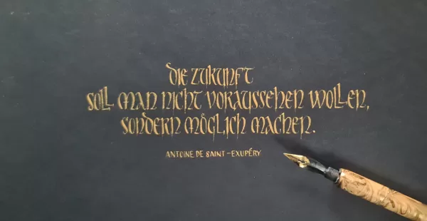 Unziale, mit Spitzfeder und Goldtinte auf schwarzem Papier geschrieben